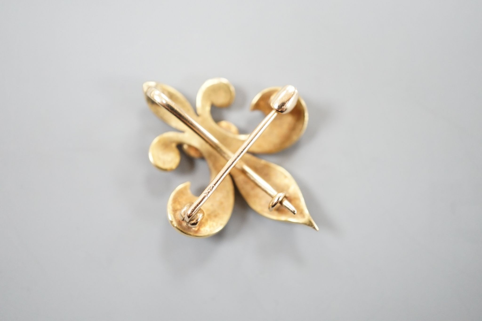 A continental 14k yellow metal, red enamel and graduated seed pearl set fleur du lis brooch, 29mm, gross weight 5.3 grams.